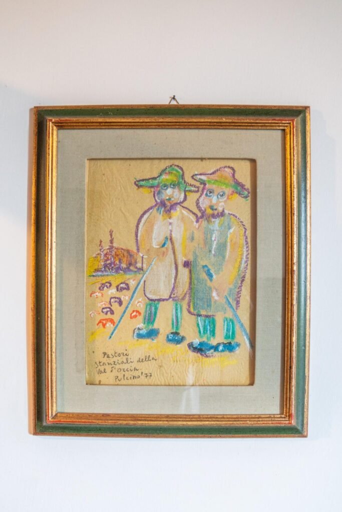 Dipinto colorato di pastori toscani, cornice dorata; atmosfera autentica delle Dimore Pulcino, Montepulciano.