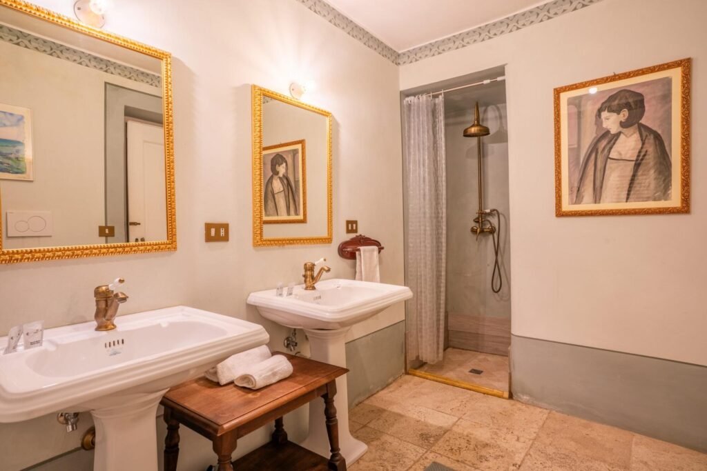 Bagno di lusso Palazzo Trecci Tombesi, specchi dorati, doppi lavabi, doccia elegante.