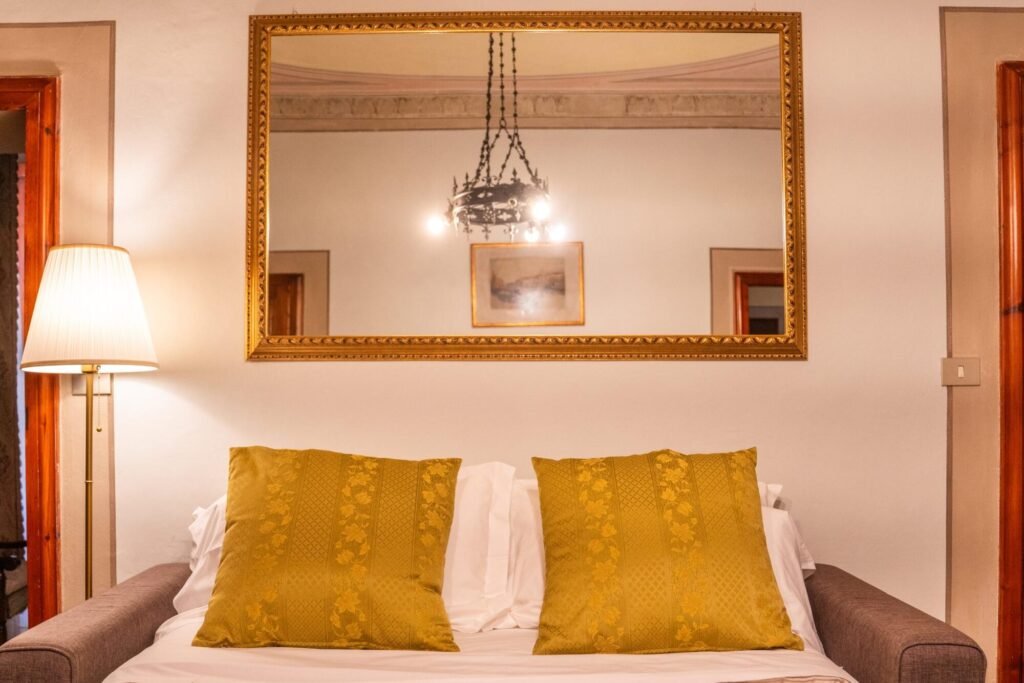 Interno elegante di Palazzo Trecci Tombesi a Montepulciano con specchio dorato e lampada.