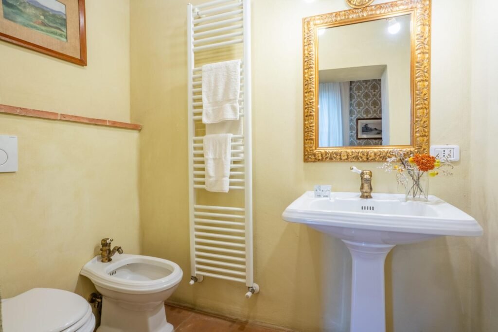 Bagno elegante con specchio dorato e lavabo di lusso a Palazzo Trecci Tombesi, Dimore Pulcino, Montepulciano.