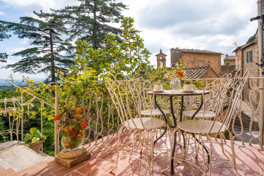 Terrazza panoramica con vista su Montepulciano, arredo vintage, ideale per un soggiorno lussuoso in Toscana.