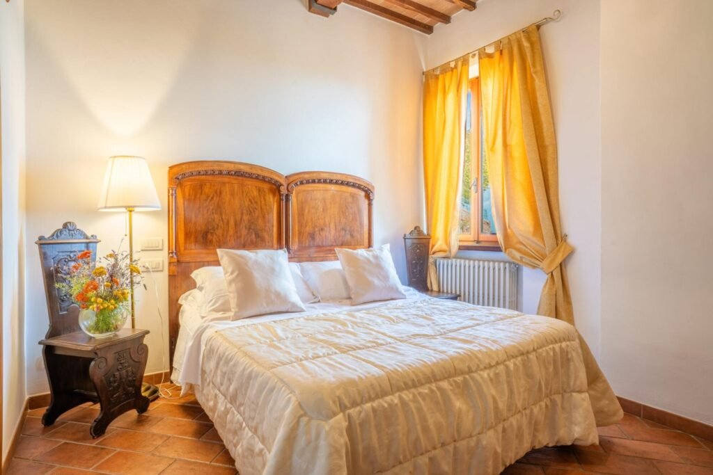 Camera da letto elegante in villa a Montepulciano, letto matrimoniale, arredi in legno, atmosfera accogliente e luminosa.