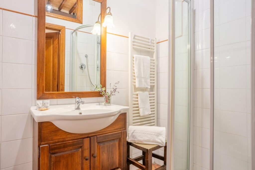 Bagno elegante con lavabo in legno e doccia, arredamento lussuoso delle Dimore Pulcino a Montepulciano.