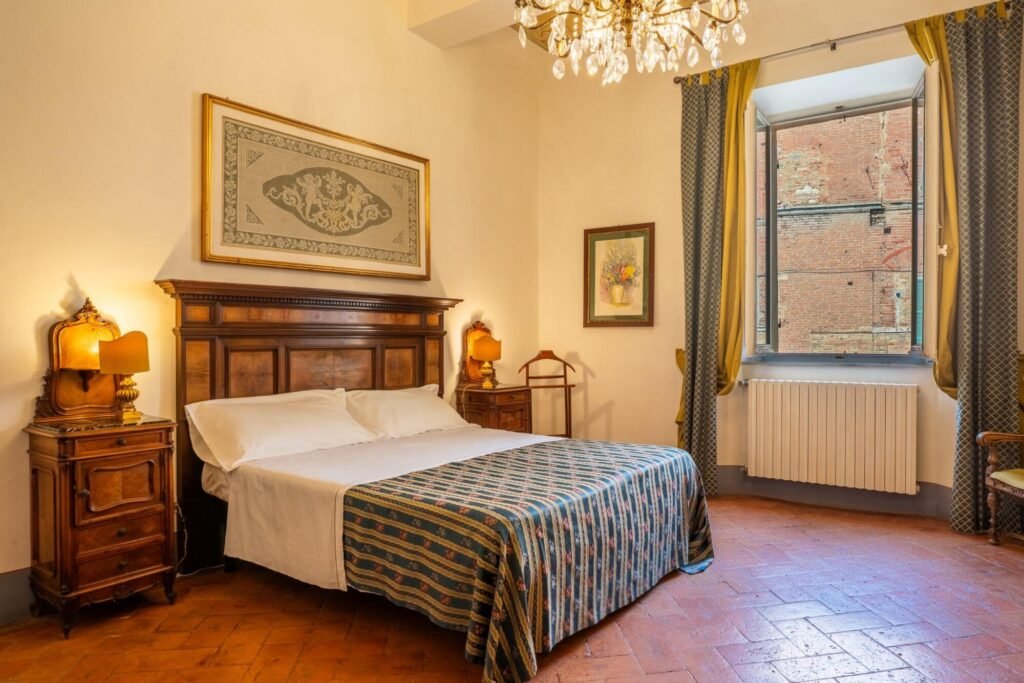 Camera elegante di Palazzo Trecci Tombesi con letto matrimoniale e arredi classici a Montepulciano.