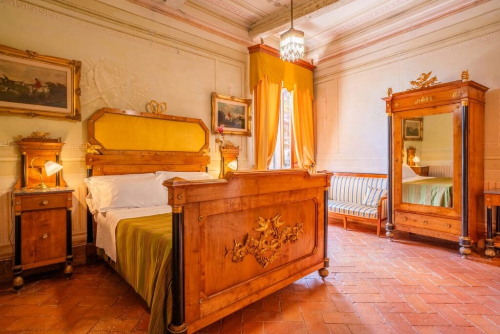 Elegante camera da letto in legno a Palazzo Trecci Tombesi, Montepulciano, con letto e mobili di lusso in stile classico toscano.