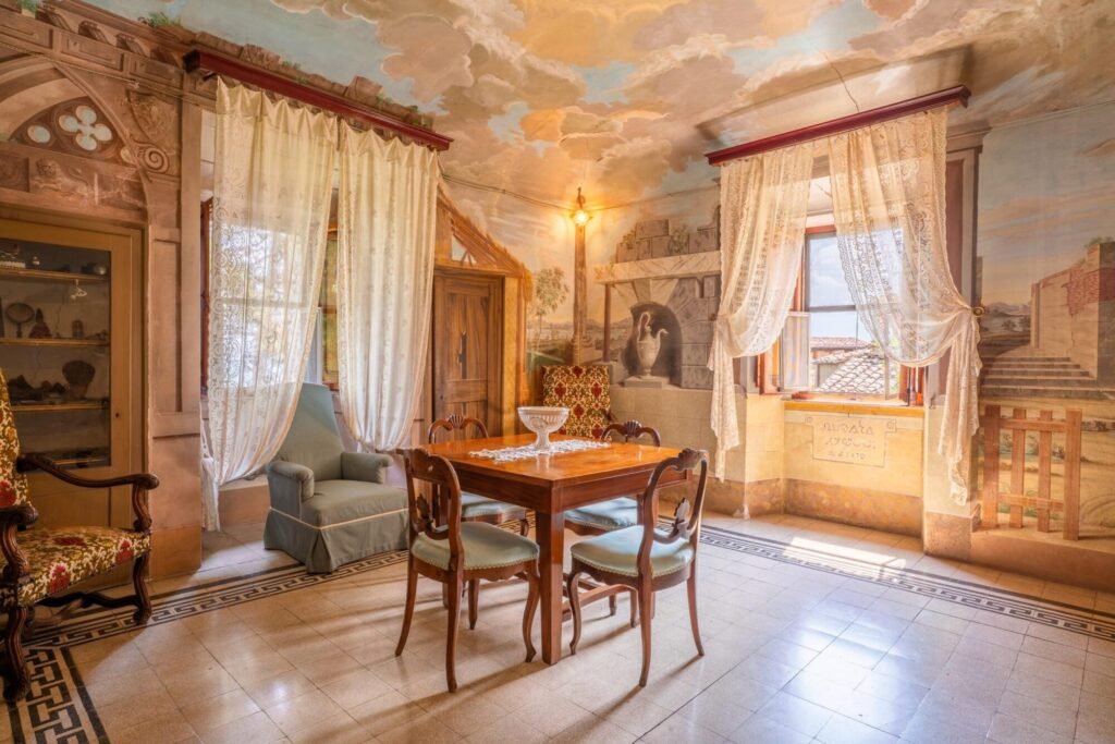 Sala elegante in stile classico con affreschi, tenda in pizzo e tavolo in legno, Palazzo Trecci Tombesi, Montepulciano.