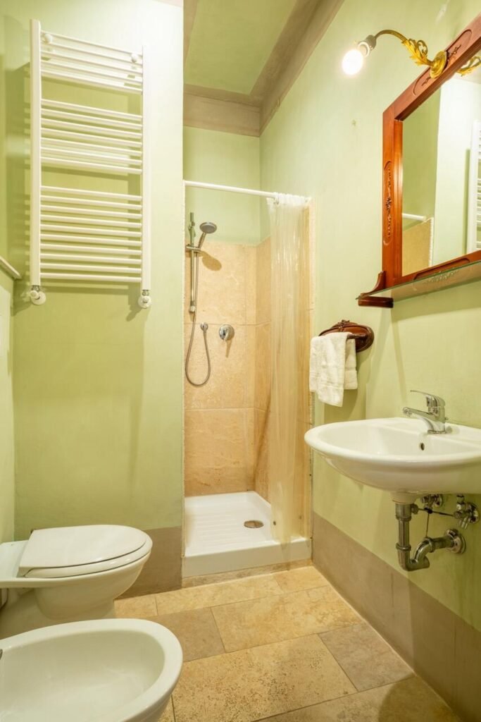 Bagno elegante in marmo chiaro con doccia e lavabo in un appartamento di lusso a Palazzo Danesi, Montepulciano.