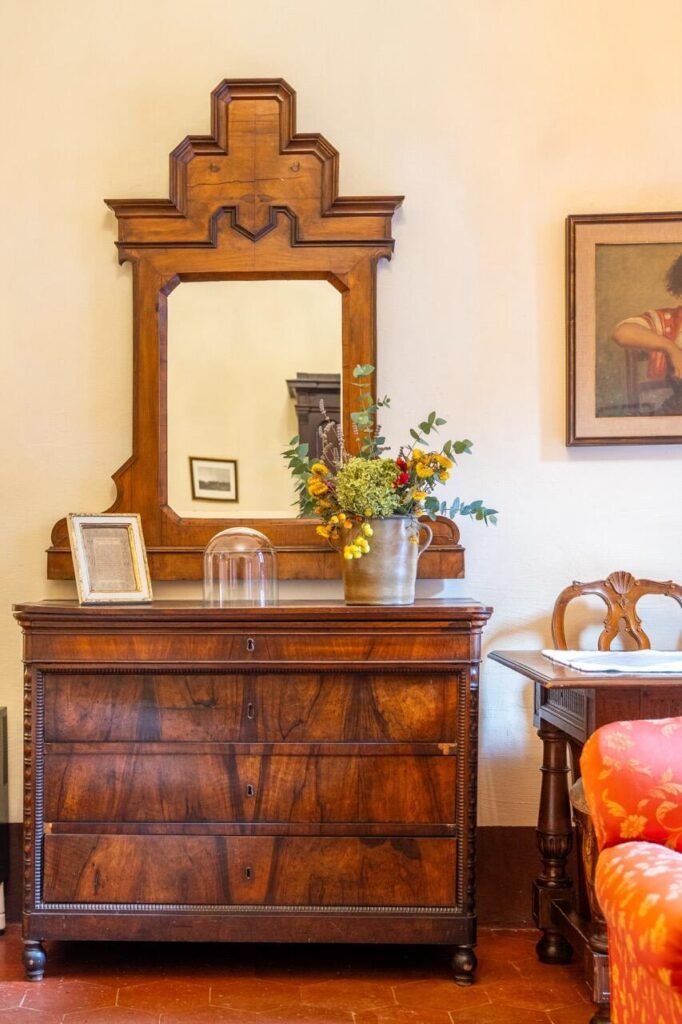 Arredo vintage in legno, specchio decorativo e fiori a Palazzo Danesi, Montepulciano, Dimore Pulcino.