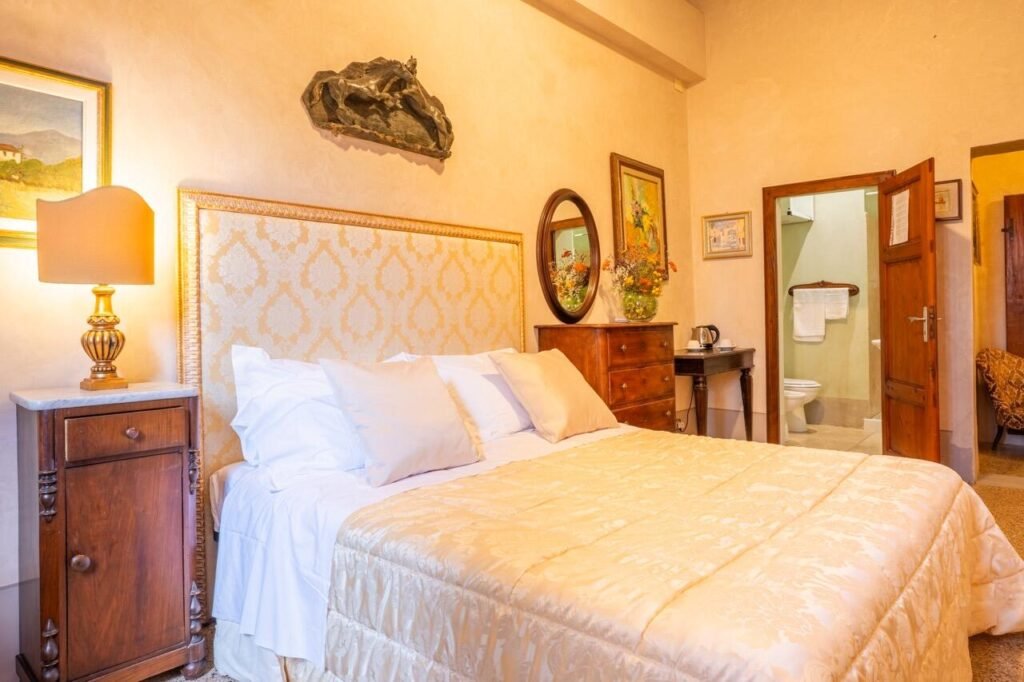 Camera da letto elegante con arredi vintage e dettagli toscani a Palazzo Danesi, Montepulciano.