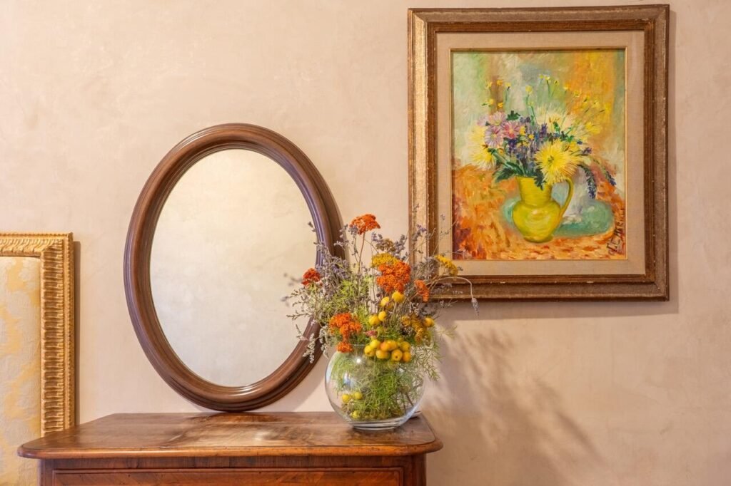 Interno elegante di Palazzo Danesi con specchio, quadro floreale e vaso di fiori, Montepulciano, Toscana.