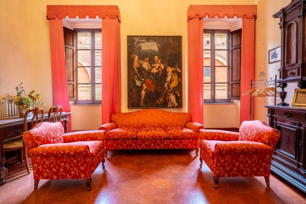 Elegante salotto di Palazzo Danesi con arredamento antico e divani rossi, lusso a Montepulciano.